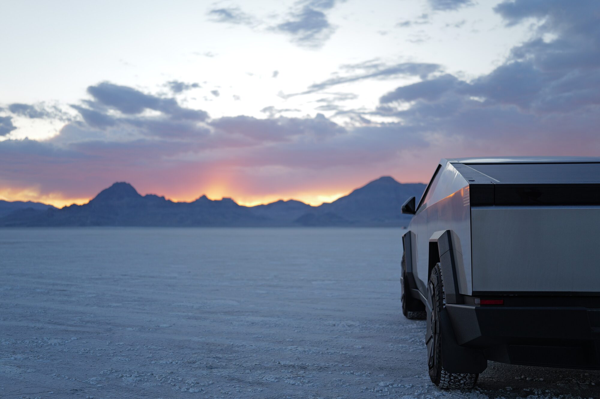 Cybertruck parked on the Bonneville salt flats at dusk, sunset glowing behind distant mountains